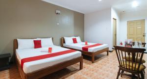 a hotel room with two beds and a chair at RedDoorz @ Balay Hiraya Apartment in Tabao
