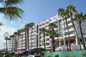 a large white building with palm trees in front of it at Les Palmiers Sunorama Beach Apartments in Larnaka