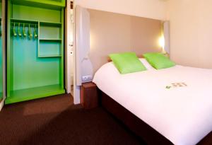 sypialnia z dużym białym łóżkiem z zielonymi poduszkami w obiekcie Campanile Metz Est Technopole - Restaurant w Metz