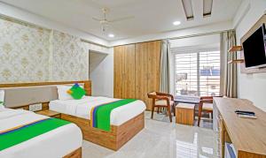 a hotel room with two beds and a desk at Treebo Trend Chandraprasth Residency in Nagpur