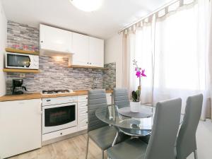 a kitchen with a glass table and chairs and a kitchen with white cabinets at Ania Apartment in Poreč