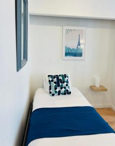 a bedroom with a bed with blue and white sheets at Hôtel Porte Mars Reims Gare Centre Arena in Reims