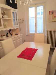 una cucina bianca con un tavolo bianco con una rosa rossa di La Casina in Paese a Montepulciano