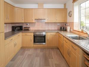 a kitchen with wooden cabinets and a sink at No 1 Railway Cottages in Betws-y-coed