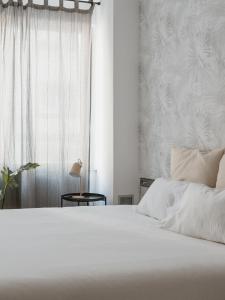 1 dormitorio con cama blanca y ventana en Apartamentos Progres, en Hospitalet de Llobregat