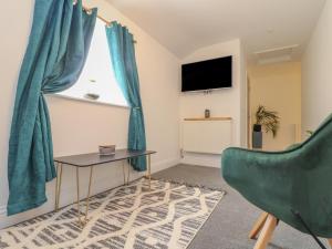 a living room with a green chair and a table and a window at Mews House in Camborne