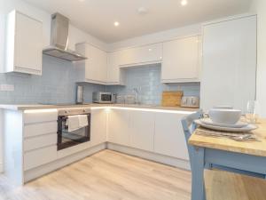 a kitchen with white cabinets and a wooden table at Mews House in Camborne