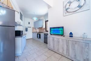 a kitchen with a refrigerator and a tv on a counter at Villa Tiziana&Alessia in Castiadas