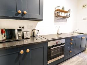 a kitchen with blue cabinets and a microwave at Sapphire Suite in Barmouth