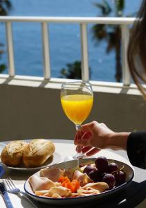 a person holding a glass of orange juice next to a plate of food at FAY Victoria Beach in Rincón de la Victoria