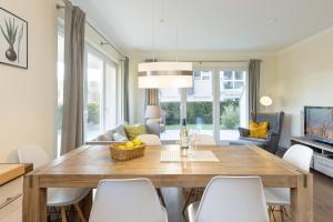 comedor con mesa de madera y sillas blancas en Baltic Sea Lodge Wohnung 1, en Scharbeutz