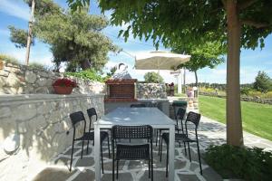 a table with chairs and an umbrella on a patio at Panorama Siviris in Siviri