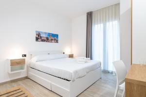 a white bedroom with a white bed and a desk at Solemar Sicilia - Multi Suite in Palermo +95 photos