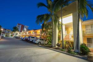 a row of cars parked in a parking lot next to buildings at Harbour Sails Motor Inn in Gladstone