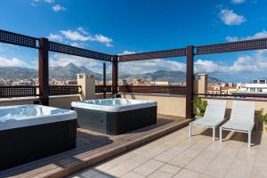 uma banheira de hidromassagem e 2 cadeiras numa varanda em Palermo Blu - Multi Suite em Palermo