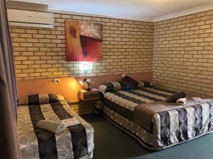 a hotel room with two beds and a brick wall at Alamo Motor Inn in Nyngan