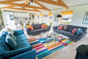 un salon avec des canapés bleus et un tapis coloré dans l'établissement Willow Cottage at Gravel Farm, à Stretham