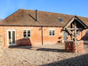 a red brick house with a gambrel roof at The Milking Parlour in Craven Arms