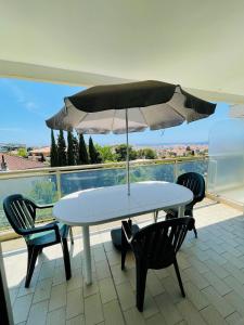 a white table and chairs with an umbrella on a balcony at Floriana in Cannes