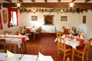 a restaurant with white tables and wooden chairs at Kenguru Panzió és Csárda in Hódmezővásárhely