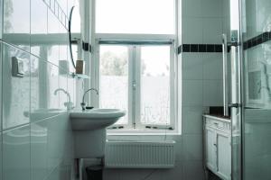 a white bathroom with a sink and a window at Bed and Breakfast du Parc in Zaandam