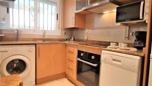 
a kitchen with a stove top oven and a microwave at ACV- Cala Blanca II-1ª Linea Planta 4 Norte 2 in Oropesa del Mar
