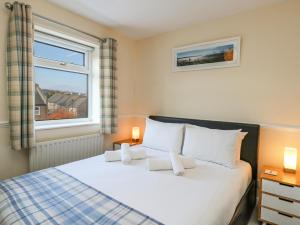 um quarto com uma cama com almofadas brancas e uma janela em Kingfisher Cottage em Weymouth