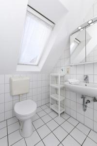a white bathroom with a toilet and a sink at Hotel-Pension Janssen - Gästehaus Huus an't Deep in Neuharlingersiel +25 photos