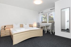 a bedroom with a bed and a table and a window at Hotel-Pension Janssen - Gästehaus Huus an't Deep in Neuharlingersiel