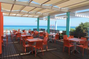 a row of tables and chairs on a deck with the beach at Serra Degli Alimini 2 in Alimini
