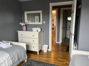 a bedroom with a white dresser and a mirror at Flat Two, 212 Eaglesham Road, East Kilbride, Glasgow in Glasgow