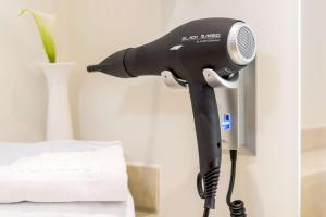 a black blow dryer is attached to a wall at NH Collection León Plaza Mayor in León