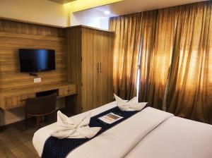 a hotel room with a bed with a flat screen tv at Hotel Manasi Royal in Satara