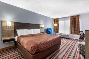 a hotel room with a large bed and a chair at Quality Inn & Suites Sulphur Springs in Sulphur Springs