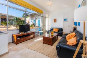 ein Wohnzimmer mit einem schwarzen Ledersofa und einem TV in der Unterkunft Cas Padri Teco in Ariany