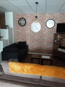 a living room with a couch and clocks on a brick wall at La Maison du Monde in Limoges