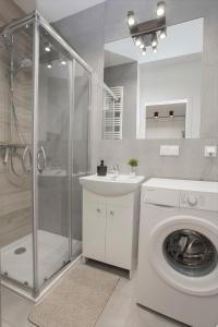 La salle de bains est pourvue d'un lave-linge et d'un lavabo. dans l'établissement Urban Jungle - Silver Apartment, à Białystok