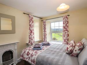 una camera con letto, camino e finestra di Smithy Cottage at Bowland Bridge a Bowland Bridge