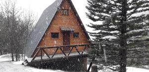 a wooden cabin in the snow with a tree at chalets montagnard in Jausiers
