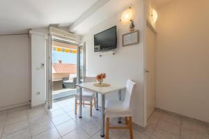 a dining room with a table and chairs and a television at Apartments Niko in Novalja