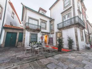 un patio avec des tables et des chaises en face d'un bâtiment dans l'établissement Maçã de Eva, à Viana do Castelo