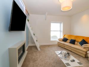 a living room with a couch and a flat screen tv at Bryngolau in Pwllheli