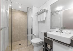 a bathroom with a toilet and a sink and a shower at H on Mitchell Apartment Hotel in Darwin