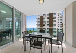 a dining room with a table and chairs on a balcony at H on Mitchell Apartment Hotel in Darwin