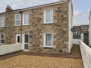 ein Backsteinhaus mit weißen Fenstern und einem Zaun in der Unterkunft Nappers Cottage in Hayle