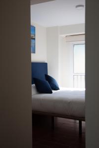 a bed with blue pillows in a room with a window at Noches en Triana in Seville