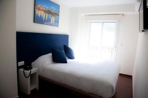 een slaapkamer met een wit bed met blauwe muren en een raam bij Noches en Triana in Sevilla