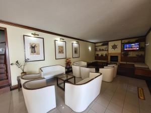 a living room with white chairs and a table at Hotel Beira Mar in Angra do Heroísmo