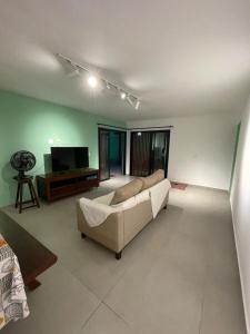 a living room with a couch and a television at Casa verde no Pontal de Maracaipe in Porto De Galinhas