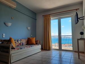 a living room with a couch and a large window at Ntemos Apartments in Tolo